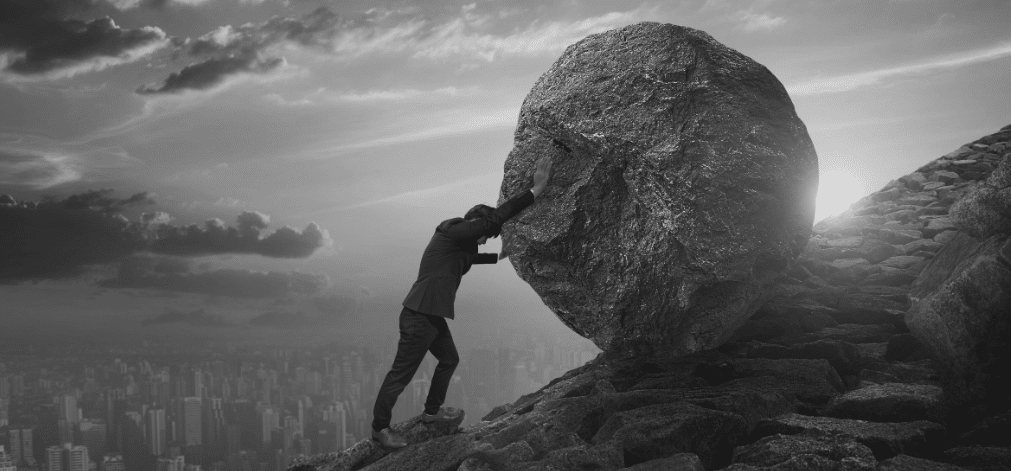 Man pushing boulder up a slope